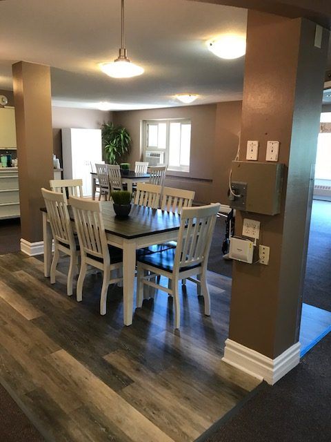 A cozy dining room setup with a wooden table and chairs, featuring wood flooring and ample natural light.