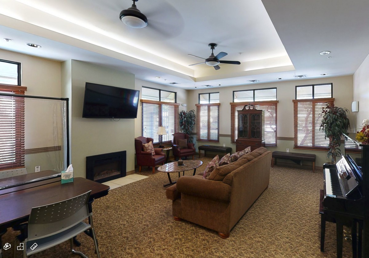 A cozy living room with a sofa, TV, and multiple windows providing natural light.