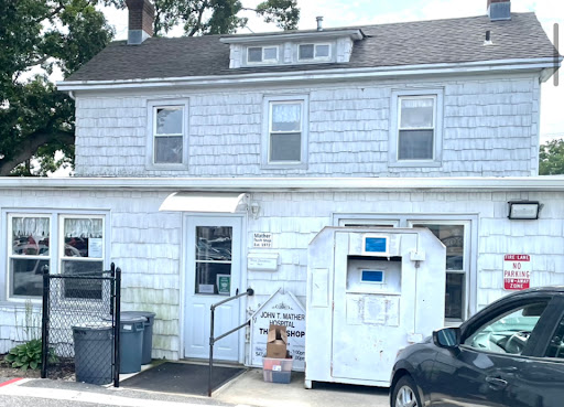 A two-story residential building with a white exterior and an entrance leading to a mailbox.