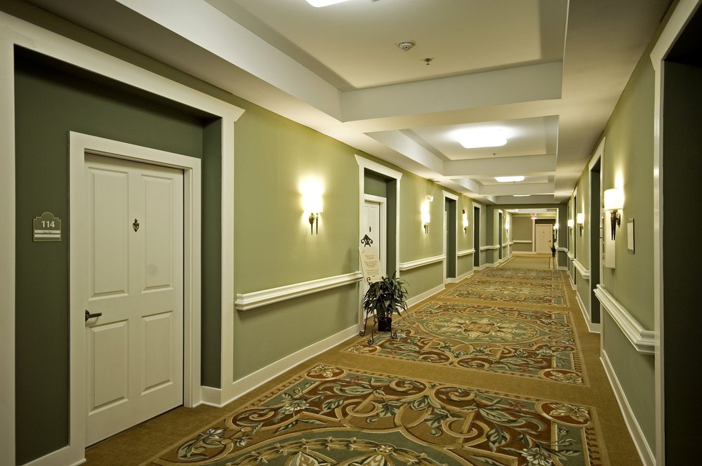 A well-lit hotel hallway with ornate carpeting and multiple doors.