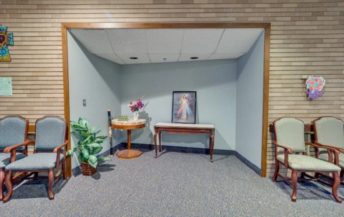 Cozy waiting area with a painting, potted plants, and a mix of furniture.