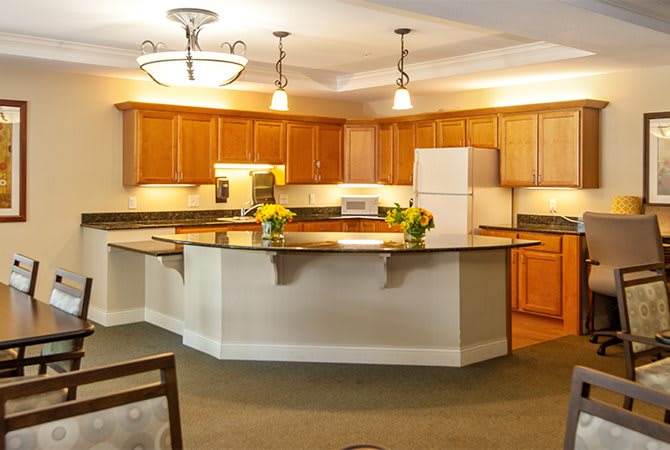 A modern kitchen featuring wooden cabinets, a center island with flowers, and ambient lighting.