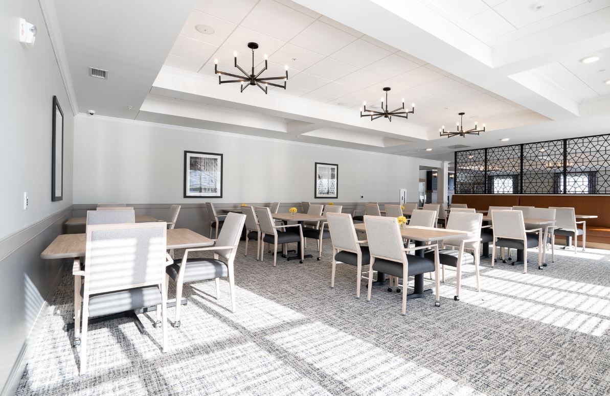 A modern restaurant dining room with elegant chandeliers and ample natural light.
