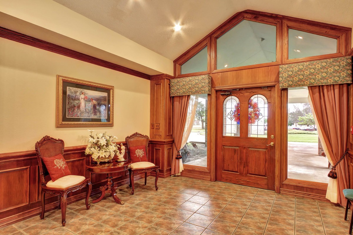 A traditional foyer with a wooden door, tiled flooring, and classic furnishings.