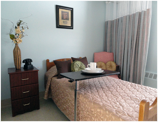 A cozy and well-decorated bedroom featuring a neatly made bed, a nightstand with a phone, and a small table set for tea.