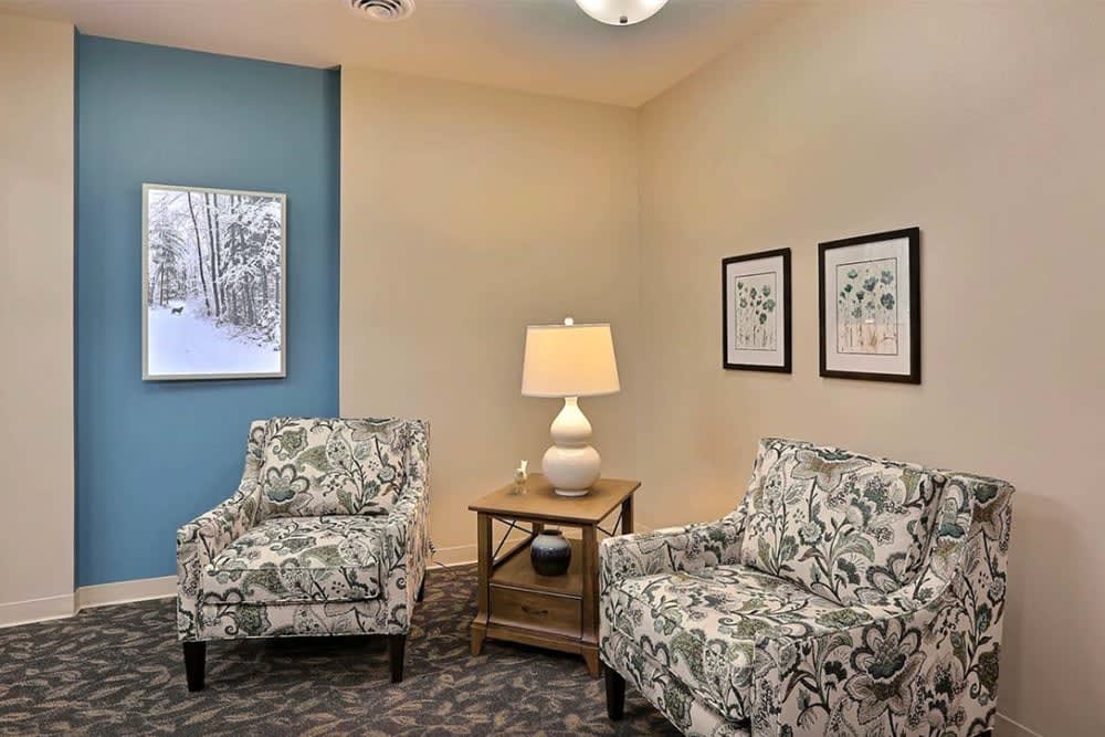 A cozy living room with patterned chairs, a wooden side table, and framed artwork on the walls.