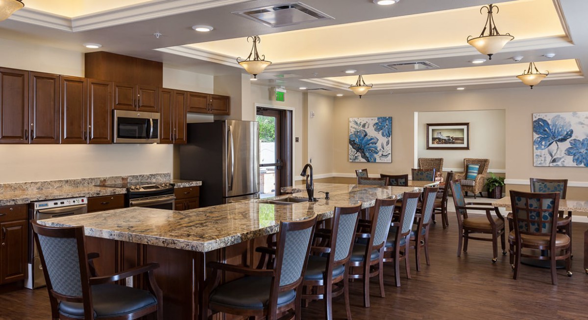 A modern kitchen and dining area with a long table and granite countertops.