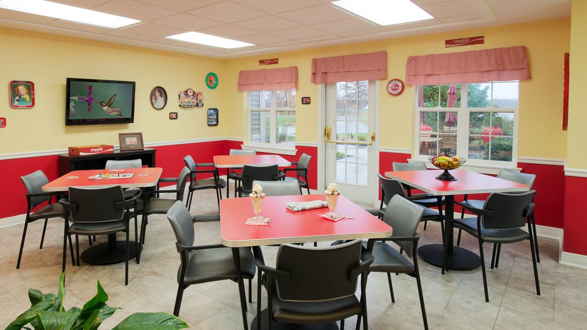 A cozy dining area with red tables and chairs, decorated with wall art and warm lighting.