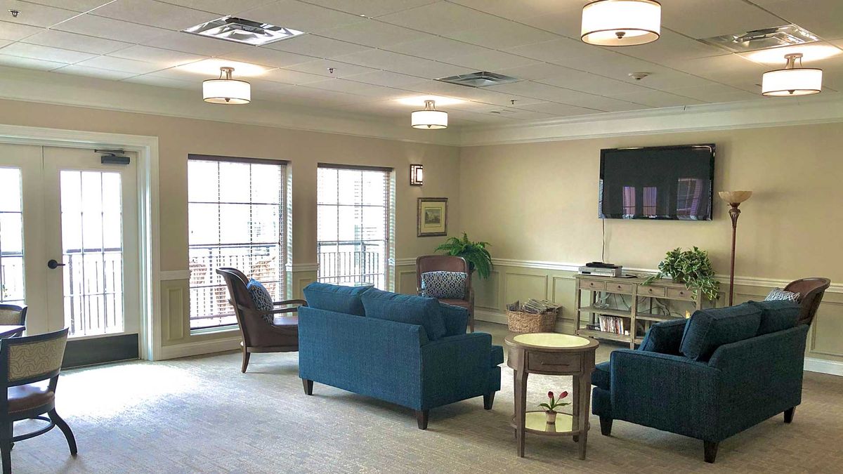 A cozy living room with a sofa, chairs, and a television on the wall.