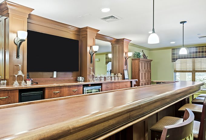 A stylish wooden bar interior with a large mirror and seating area.