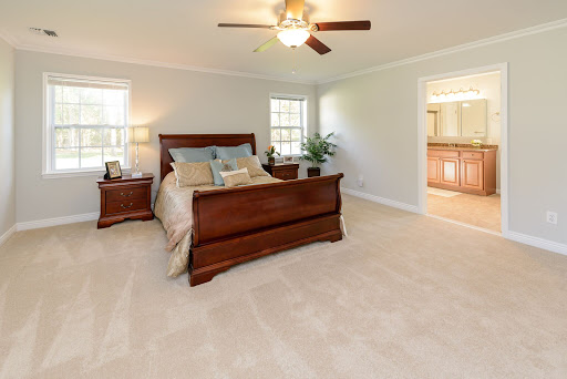 A cozy and well-lit bedroom featuring a wooden bed set and ceiling fan.