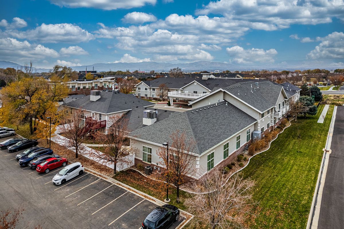 Aerial view of a suburban area with residential buildings and a parking lot under a cloudy sky.