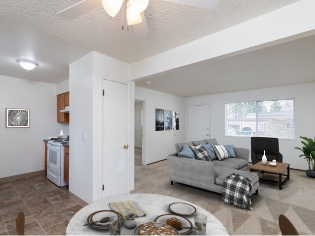 A modern open-plan living space featuring a cozy sofa, coffee table, and adjacent kitchen and dining areas.