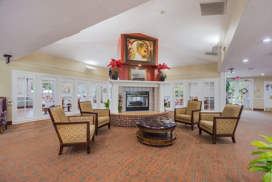 A cozy living room with a central fireplace, surrounded by upholstered armchairs and a round coffee table.