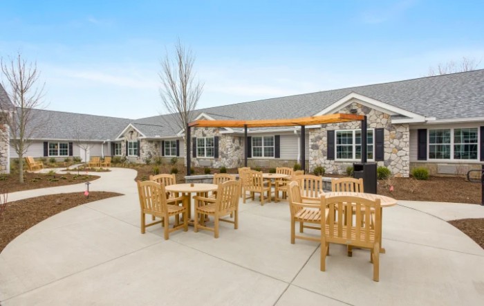 A patio area with wooden furniture in front of a residential building.