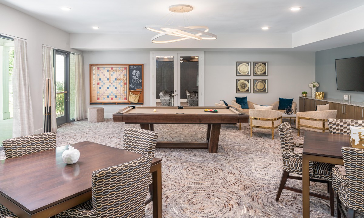 A stylish and modern game room featuring a pool table, comfortable seating, and contemporary artwork.