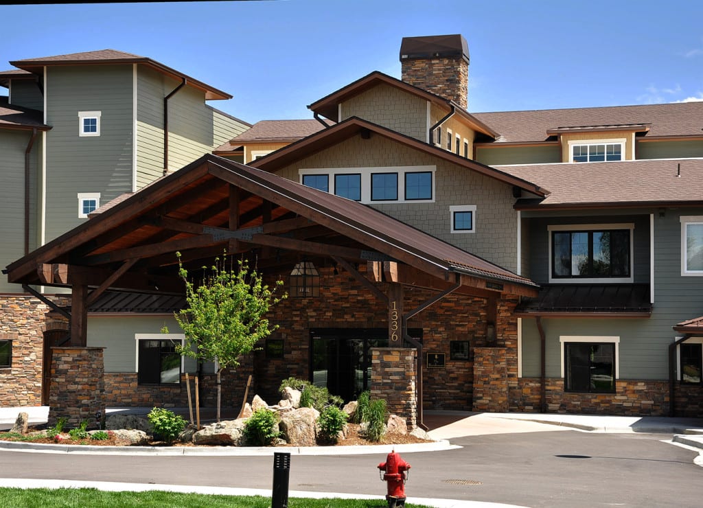 A modern residential building with a covered entrance and landscaped surroundings.