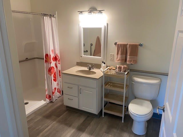 A clean and organized bathroom with a shower, sink, and toilet.