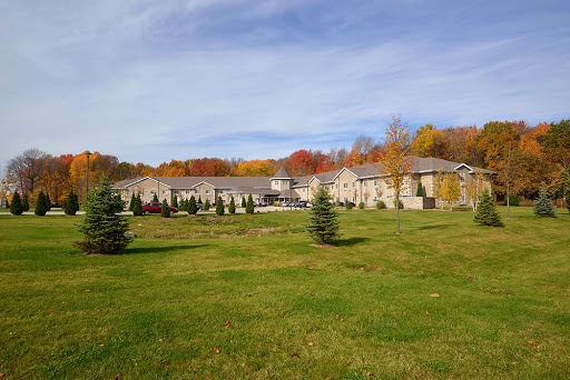 A scenic view of a large building surrounded by a lawn and colorful autumn trees under a clear sky.