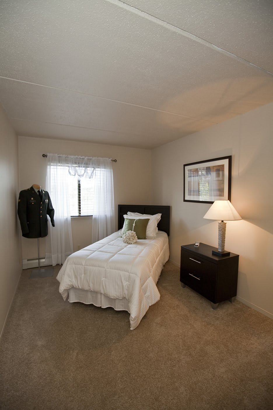 A minimalist bedroom with a single bed, nightstand, and lamp.