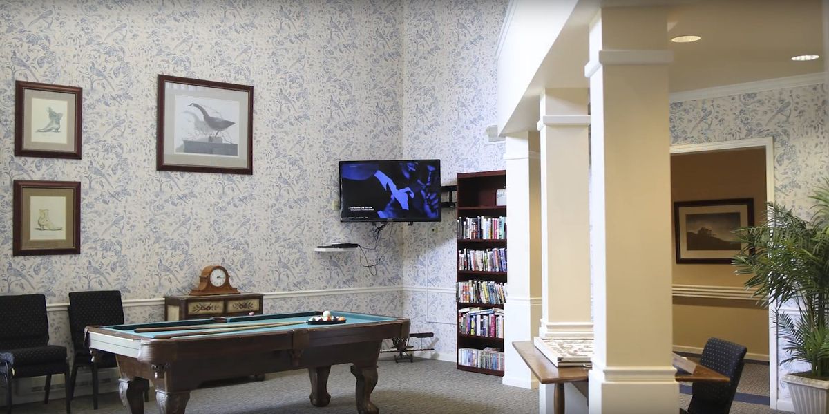 A cozy game room featuring a billiard table, TV, and bookshelf.