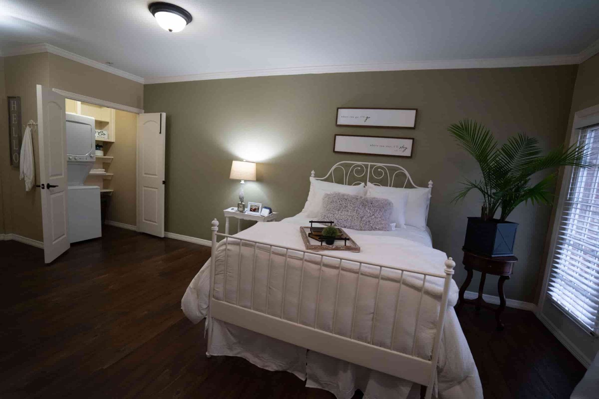 A cozy bedroom with a neatly made bed, a bedside lamp, and decorative elements.