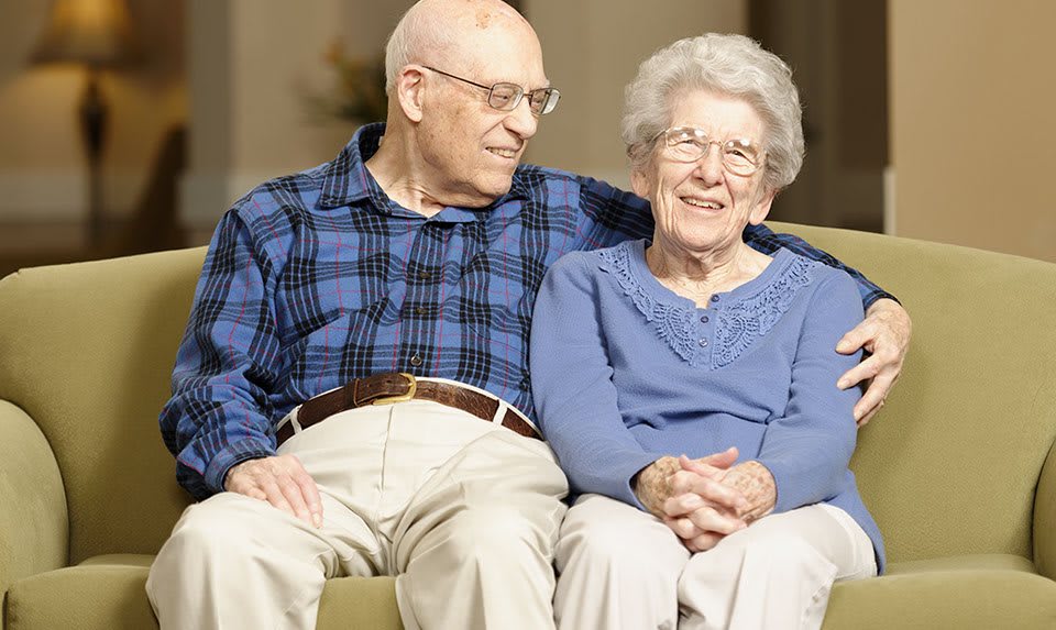 An elderly couple sitting together and smiling.