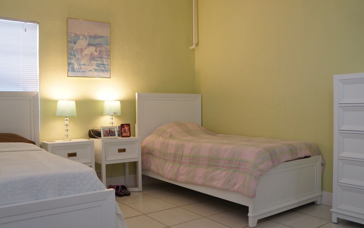A cozy bedroom with twin beds and a shared nightstand with two lamps.
