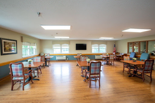 A spacious dining area featuring wooden tables and chairs, with ample natural light from large windows.