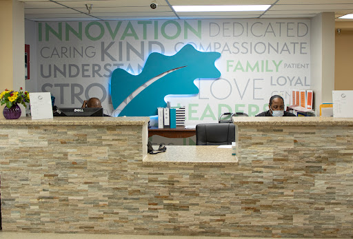 A welcoming reception area with two staff members behind the front desk, featuring a modern design and inspirational wall words.