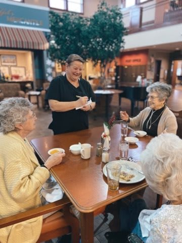 A waitress taking an order from a group of seniors enjoying a meal together.