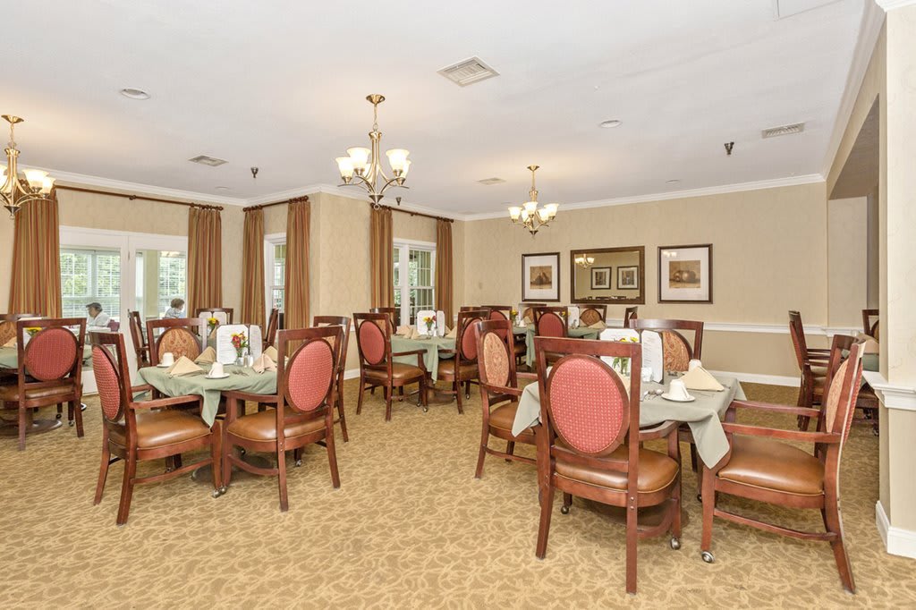 An elegant dining room with neatly arranged tables and chairs, adorned with chandeliers.