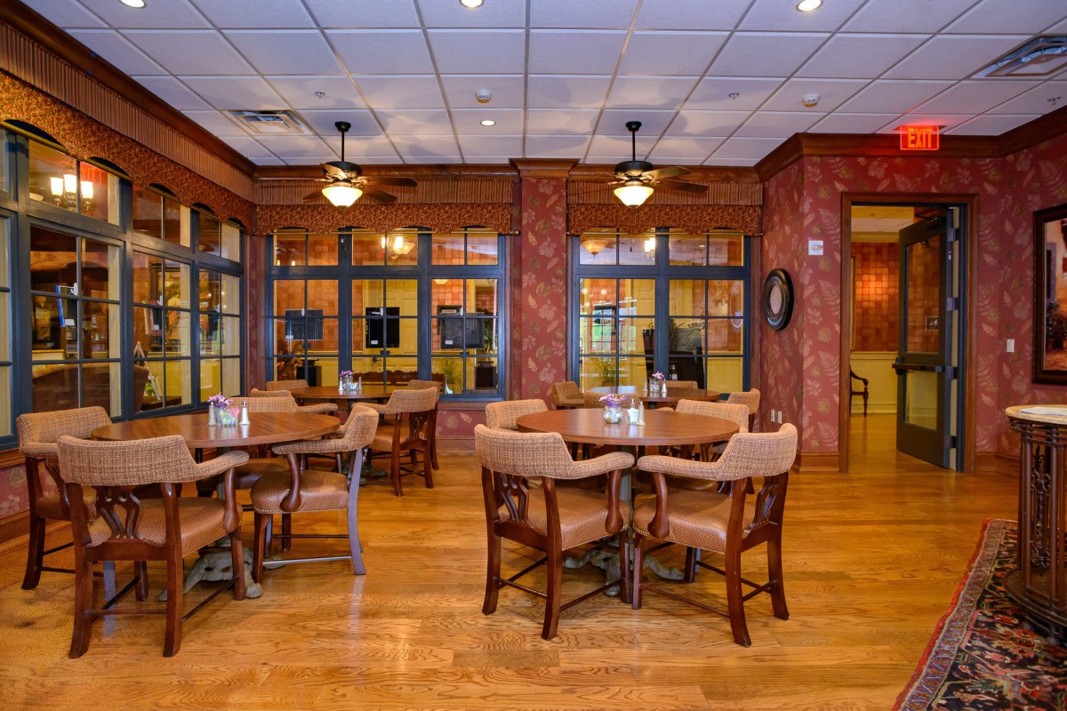 Cozy restaurant interior with wooden flooring and neatly arranged tables and chairs.