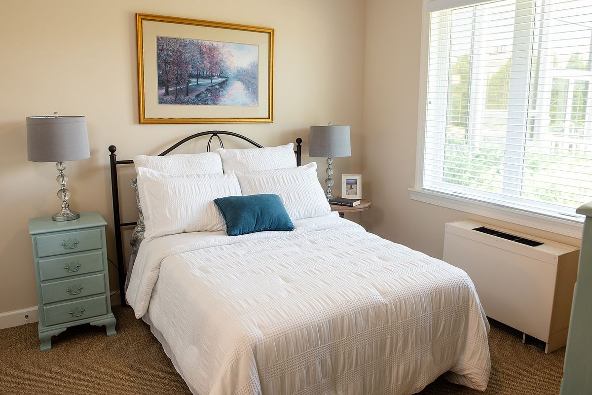 A cozy, well-lit bedroom with a neatly made bed and tasteful decor.