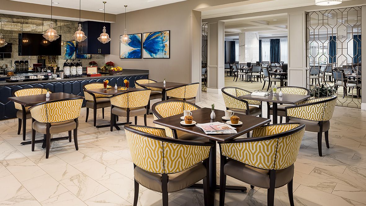 A modern restaurant dining area with tables and chairs, featuring contemporary artwork on the walls.
