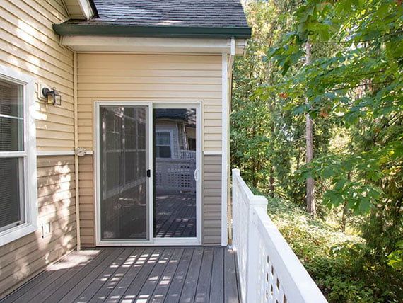 A house with a wooden deck and sliding glass door, surrounded by trees.