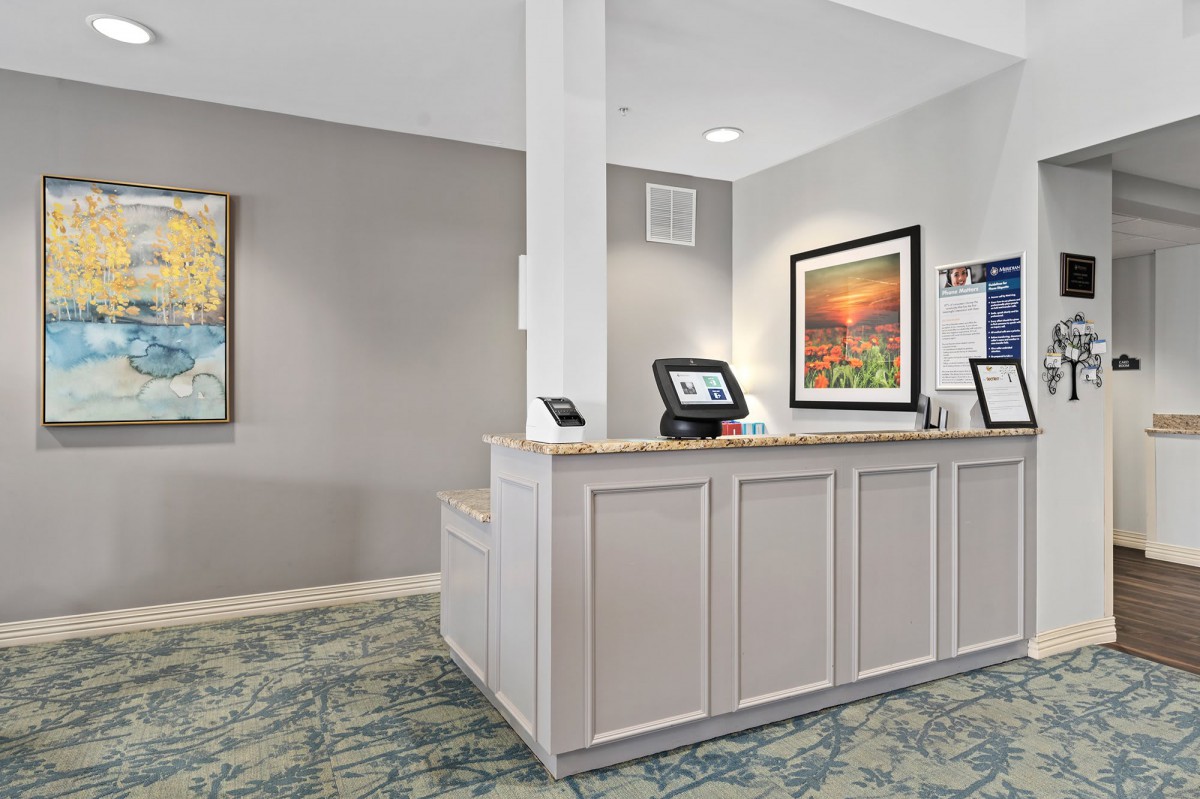 A hotel reception area with a front desk and artwork on the walls.