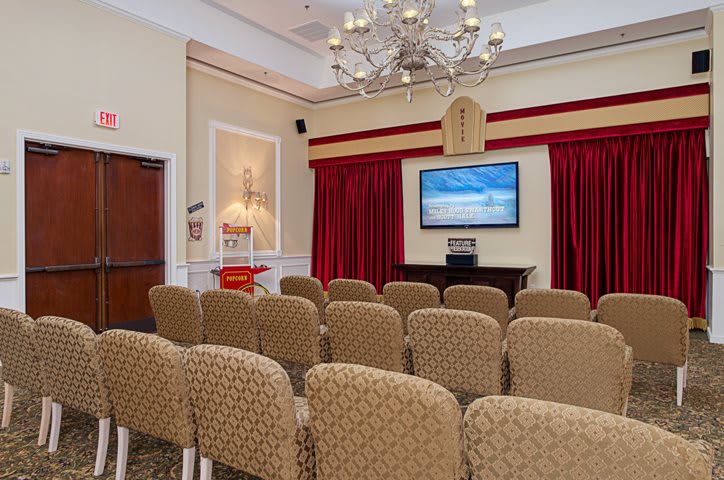 A conference room with rows of chairs facing a projection screen and a chandelier overhead.