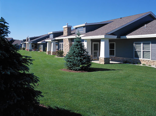 A row of modern single-story homes with manicured lawns under a clear blue sky.