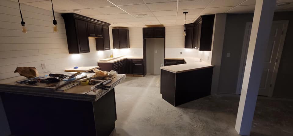 A modern kitchen under construction with dark cabinets and illuminated countertops.