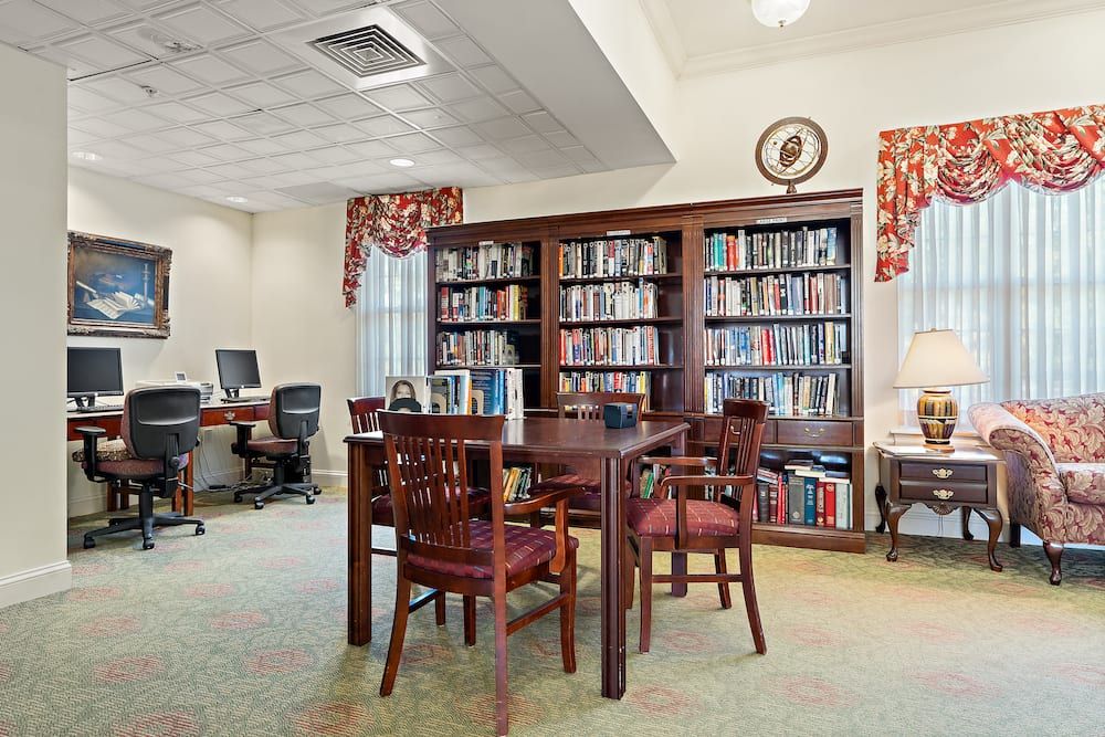 A cozy library reading area with bookshelves, tables, and computers.