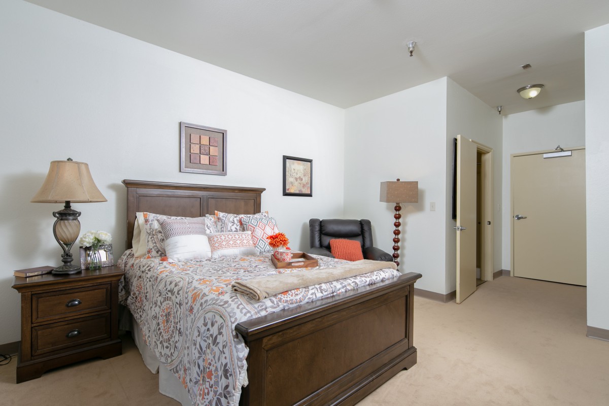 A cozy bedroom with a large bed, featuring stylish decor and warm lighting.