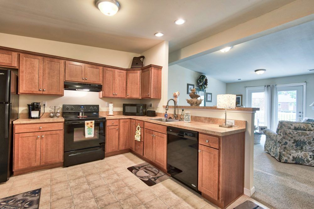 A modern kitchen with wood cabinets, black appliances, and an open layout.