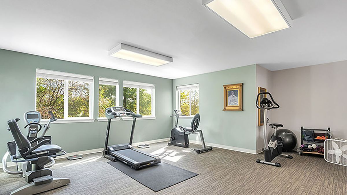 A well-lit gym with a treadmill and stationary bike.