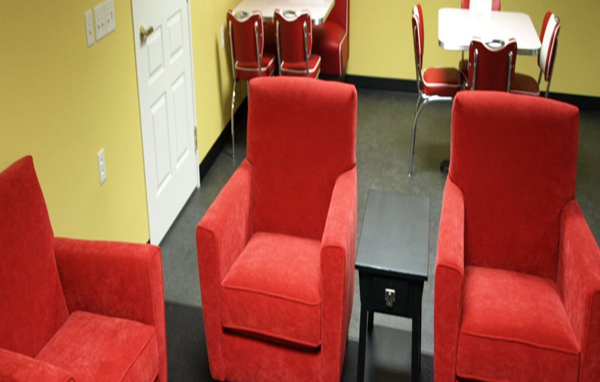 A cozy living room with red armchairs and a small black table.