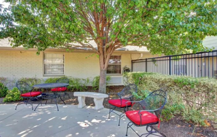 A cozy outdoor patio area with chairs and a table under a tree.