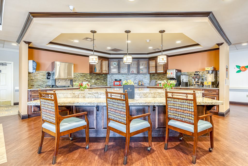 A modern kitchen interior featuring a central island with chairs and pendant lighting.