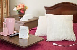 A cozy bedroom setup featuring pillows, a flower arrangement, and decorative elements.