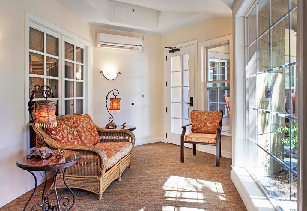 A cozy sunroom with wicker furniture, large windows, and ample natural light.