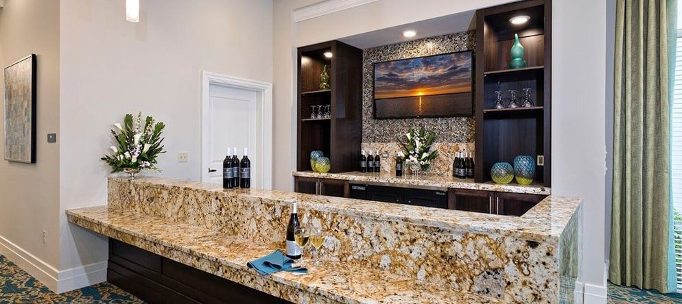 A modern kitchen setup featuring a granite countertop and wine bottles on display.